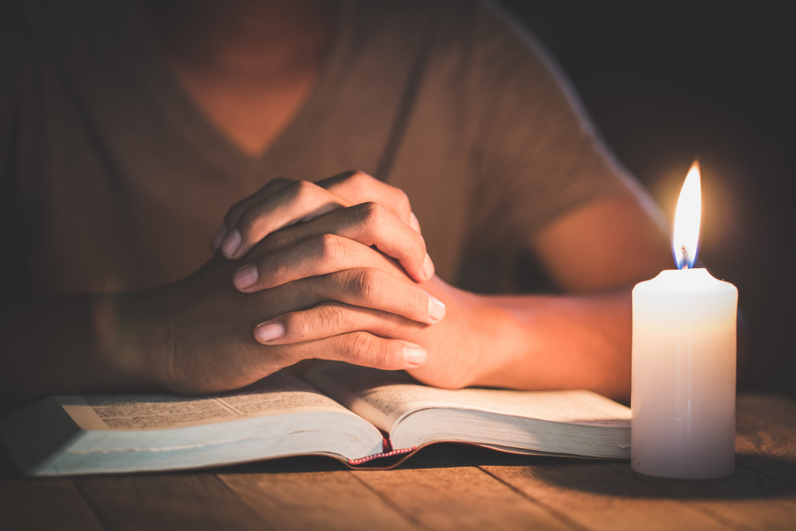 Hand boy praying In the room and lit candles to light , Hands folded in prayer concept for faith, spirituality and religion